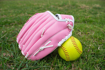 Green softball and pink softball glove on field