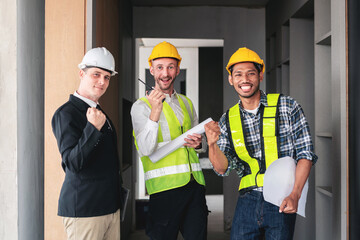 Three men in construction gear are smiling and holding papers