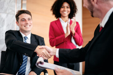 A man shakes hands with a woman in a red jacket