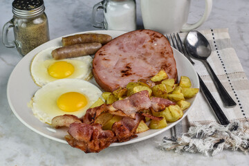 two fried eggs  served with bacon, sausage and ham