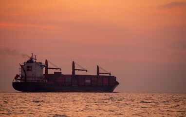 Obraz premium Silhouette cargo shipping transportation logistic commerce industry loading export on open sea with sun sky background