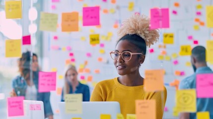 Woman placing sticky notes on a whiteboard full of colorful notes in a creative office environment. Concept of brainstorming and planning.