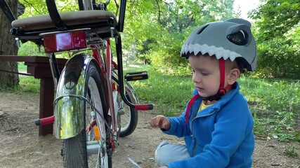 child little boy with wrench playing unscrewing nuts on bicycle in summer park