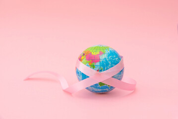 globe earth with pink ribbon on pink background, Global breast cancer awareness concept