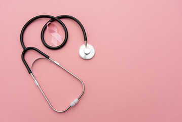 Breast cancer awareness. Pink ribbon sign with stethoscope on pink background with copy space