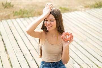 Teenager girl holding a donut at outdoors has realized something and intending the solution
