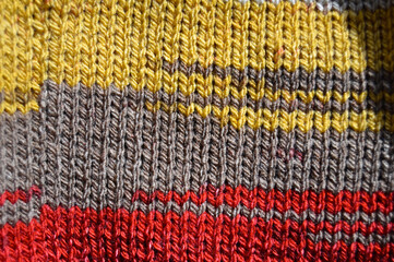 Handmade knitted fabric red yellow and beige wool background texture