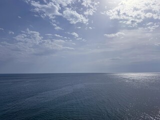 Ocean blue water with sun glare and sky clouds