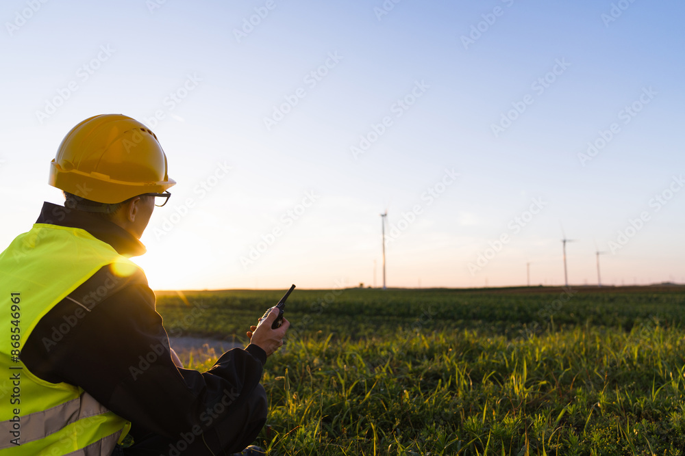 Aufkleber worker with digital tablet sits on the grass and looks at wind turbines