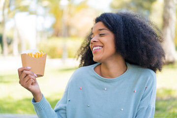 Young African American woman holding fried chips at outdoors with happy expression