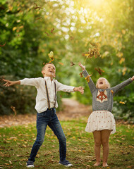 Girl, boy and children with leaves, fall and playing with smile, excited and bonding on holiday in...