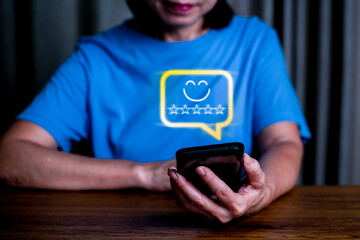 Close up woman hand holding smart phone  and show the smile face emoticon on the virtual touch screen ,give five star symbol, Customer service and business satisfaction survey.