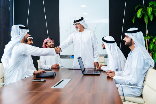 Group of corporate arab businessmen meeting in the office - Business people wearing traditional emirati kandura working together in Dubai