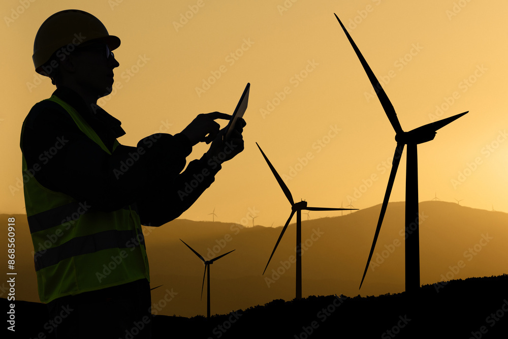 Aufkleber engineer with digital tablet works on a field of wind turbines at sunset