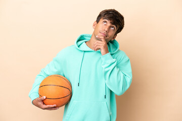 Handsome young basketball player man isolated on ocher background having doubts