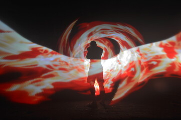 One person standing alone against a Colourful circle light painting as the backdrop