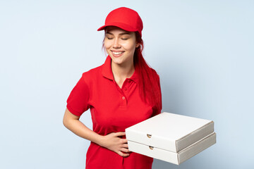 Pizza delivery girl holding a pizza over isolated background smiling a lot