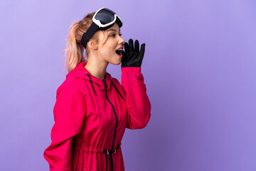 Skier teenager girl with snowboarding glasses over isolated purple background shouting with mouth wide open to the side