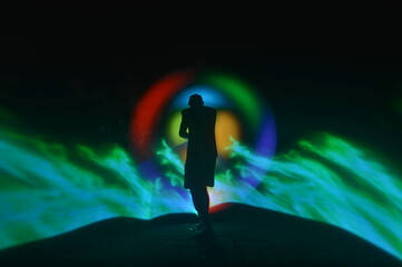 One person standing alone against a Colourful circle light painting as the backdrop