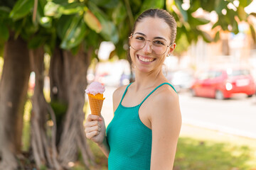 Young pretty woman with a cornet ice cream at outdoors smiling a lot