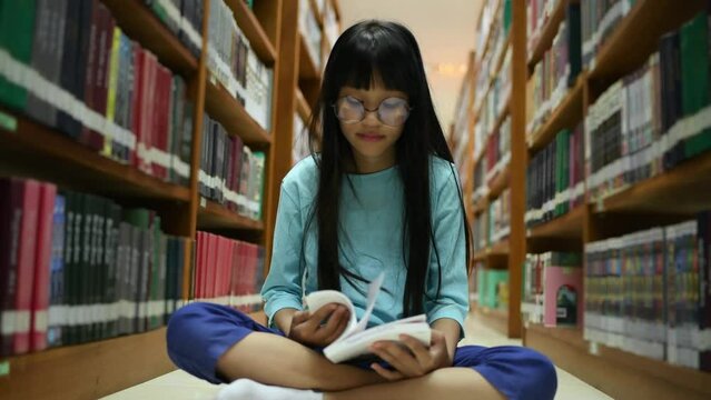 Little girl posing in public library room selecting for reading. girl chooses books on shelves learning from books is school education benefits of everyday.