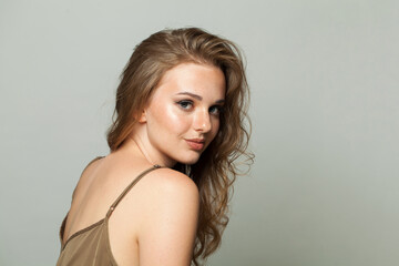 Fototapeta premium Lovely female face. Woman with makeup, curly hairstyle and fresh skin on white background