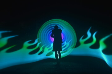 One person standing alone against a Colourful circle light painting as the backdrop