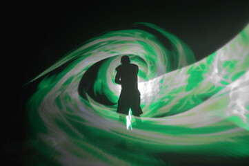 One person standing alone against a Colourful circle light painting as the backdrop	