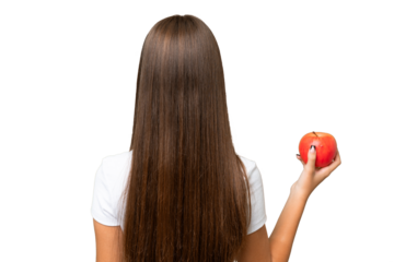 Teenager caucasian girl holding an apple over isolated background in back position