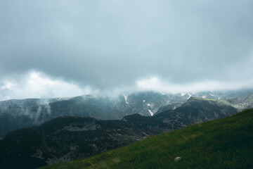 Epic and moody landscape view of the Rila Mountains covered with fog and clouds. Bulgaria.