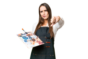 Young artist woman holding a palette over isolated chroma key background showing thumb down with...