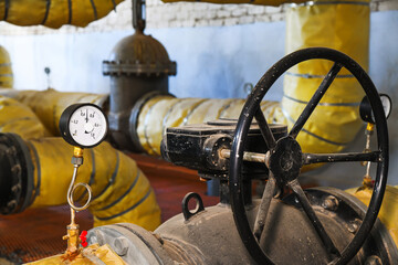 Pipes, shut-off valves and pumps of the heating system in an industrial boiler room
