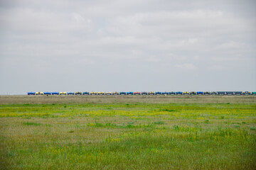 Fototapeta premium Locomotive pulls a very large and heavy freight train with wagons and tank cars along a railway