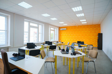 School desks with laptops in an empty modern classroom