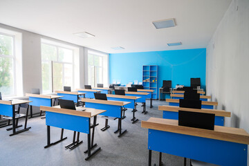 School desks with laptops in an empty modern classroom