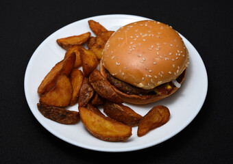 Hamburgers and homemade potatoes on a white plate. Delicious breakfast. Fast food.