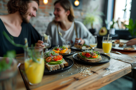 couple sitting at a modern dining table, sharing a healthy vegan breakfast. The table is set with plates of avocado toast garnished with cherry tomatoes, sprouts, and sesame seeds,