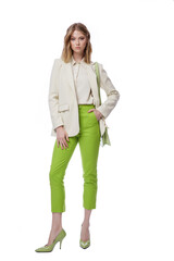 High fashion photo of a beautiful elegant young woman in pretty green pants, trousers, jacket,  handbag posing on white background. Slim figure. Blonde