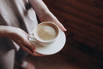 White cup of morning tasty coffee in the hand