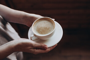 White cup of morning tasty coffee in the hand