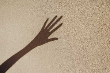 Shadows of hand on the wall asking for help . Abstract blurred effect with space for text.