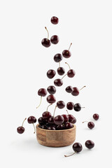 Cherries falling into a plate on a white background