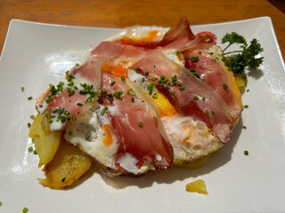 Delicious traditional Tyrolean mountain dish with cut grilled potatoes, speck and eggs. View from the top. Calorie dish