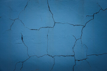 A blue wall with cracks and holes