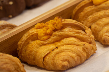 A pastry with a yellow topping sits on a white plate