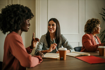 Two smiling young internship talking during an office meeting