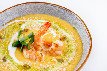 Pumpkin cream soup with shrimp. On a white background, isolated.