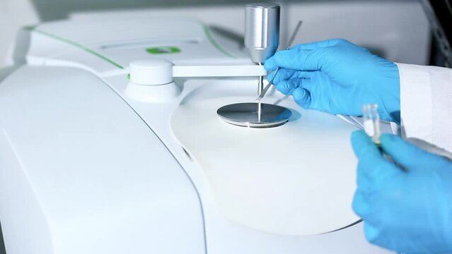 Scientists use stainless spatula to scoop substances into pedestal instrumentation of Fourier Transform Infrared Spectroscopy (FTIR) to analyze drugs, organic compounds to identify chemical identity.