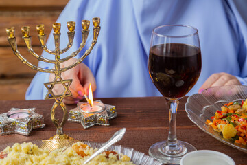 The hands of a Jewish woman at the Pesach Seder table light candles