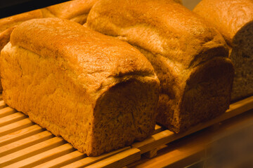 Three loaves of bread are displayed on a wooden shelf